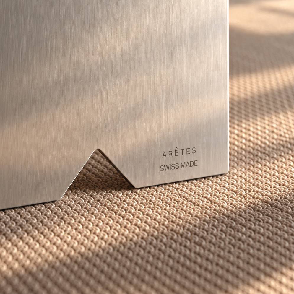 Close-up of brushed stainless steel with the engraved ARÊTES Swiss Made mark