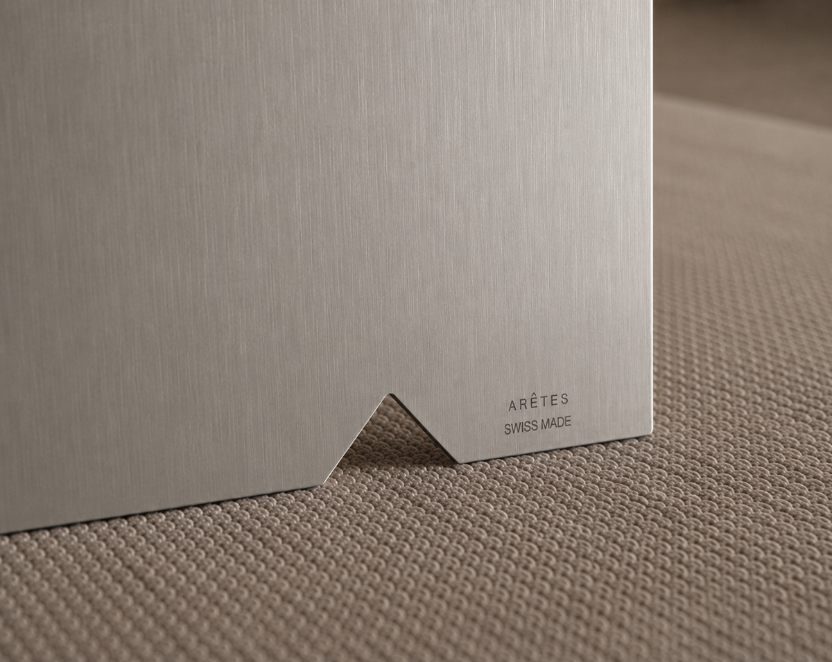 Close-up of brushed stainless steel with the engraved ARÊTES Swiss Made mark